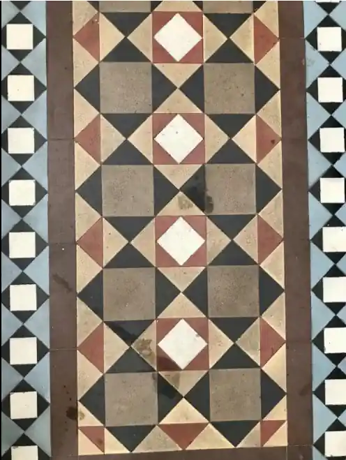 A tiled floor with a pattern of squares and triangles in a narrow hallway.