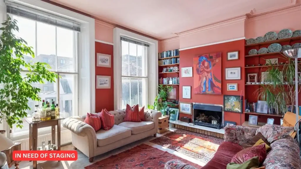 A living room with red walls and a fireplace in need of staging before the sale.