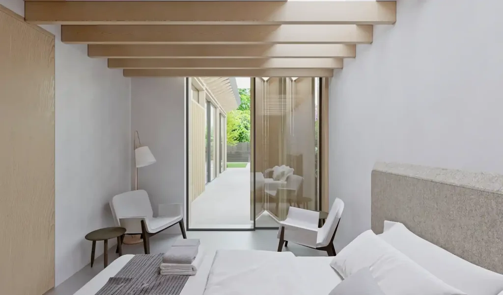 Modernly furnished bedroom with minimalist decor in a Golf Course House, featuring a glass wall leading to an adjoining patio.