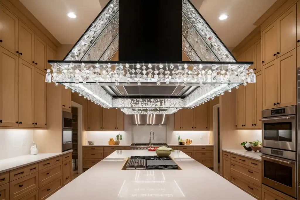 Modern kitchen with wooden cabinetry, a large central island, and a distinctive, illuminated crystal chandelier hood over the stove, all thoughtfully designed.