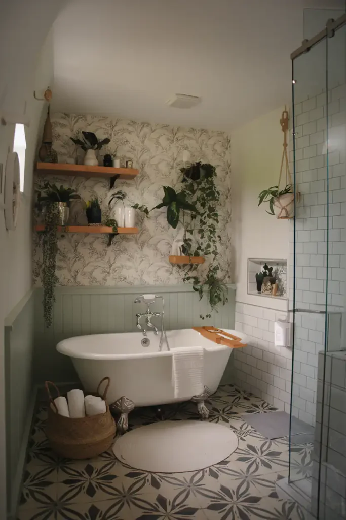 A cozy bathroom with a clawfoot tub, potted plants on shelves, green walls, patterned floor tiles showcasing the pros and cons of various bathroom flooring materials, and a glass shower.