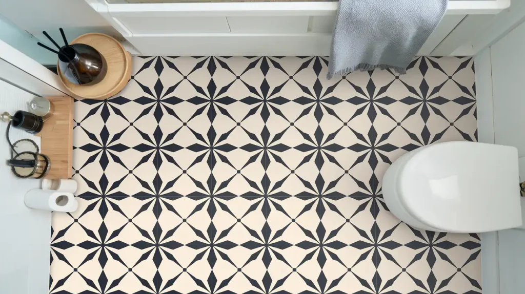 Bathroom with patterned black and white floor tiles, a white toilet, a towel, and various small items on the floor. When considering bathroom flooring materials, each option offers different pros and cons to suit your style and needs.