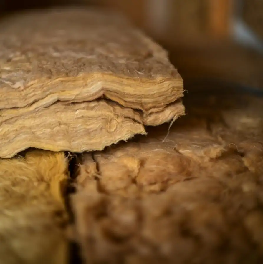 Close-up of stacked brown cellulose fiber paper insulation material with a rough texture, ideal for insulating post-frame buildings or pole barns.