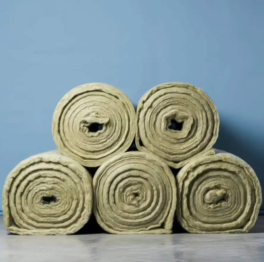 Five rolls of insulating material stacked against a blue wall, ideal for enhancing the energy efficiency of your post-frame building.