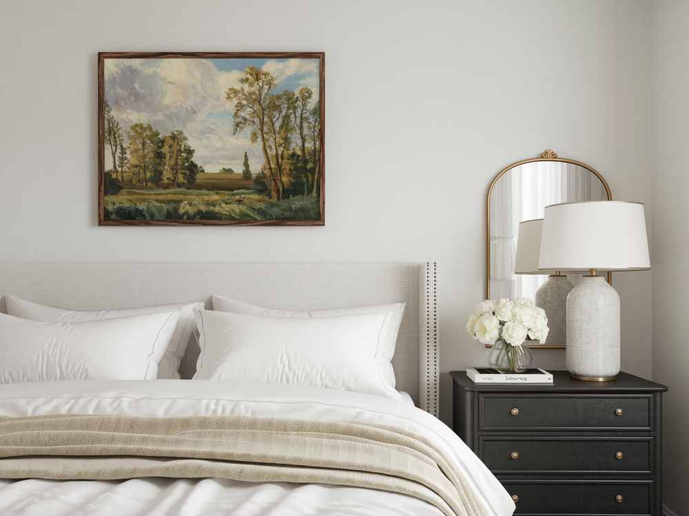 A guest bedroom featuring a neatly made bed, landscape painting, and a side table adorned with a lamp, mirror, and vibrant flowers evokes the elegance of a luxury hotel.