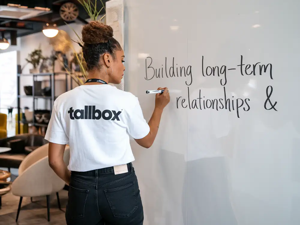 In a casual office setting, a person writes "Building long-term relationships & Guest Blogging" on a whiteboard, laying the foundation for innovative strategies.