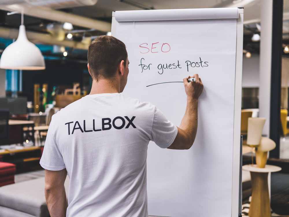 In an office setting, someone is diligently writing "SEO for guest blogging" on a flip chart, strategizing ways to optimize digital visibility.