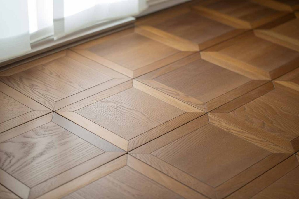 Geometric wood parquet flooring near a window with sheer white curtains letting in natural light adds timeless elegance and boosts property value.