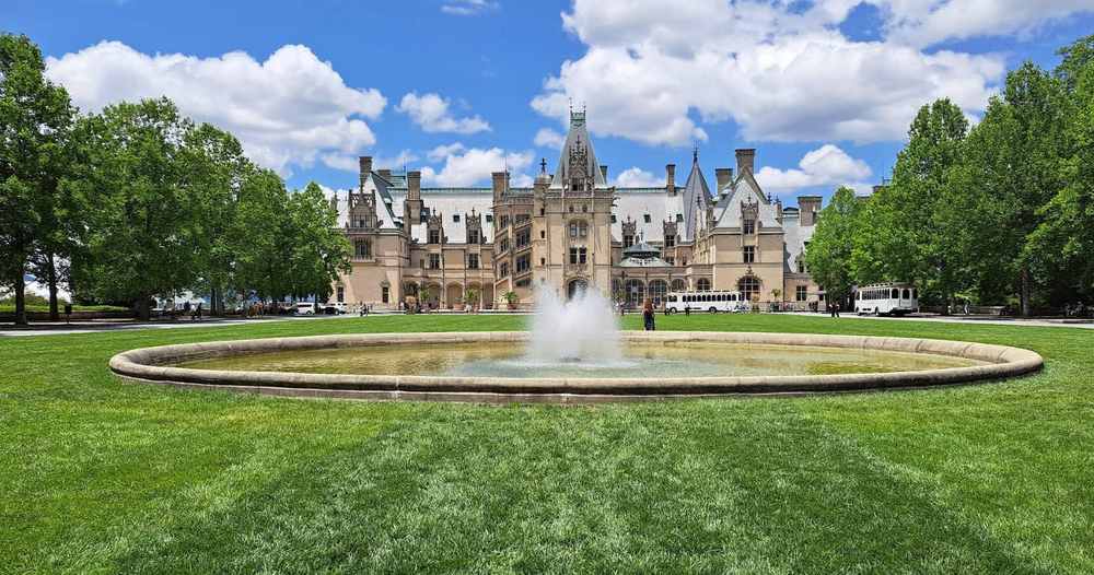 The large historic Baltimore mansion with a central fountain on a green lawn, surrounded by trees under a blue sky—an inspiring example for any house sizing guide.