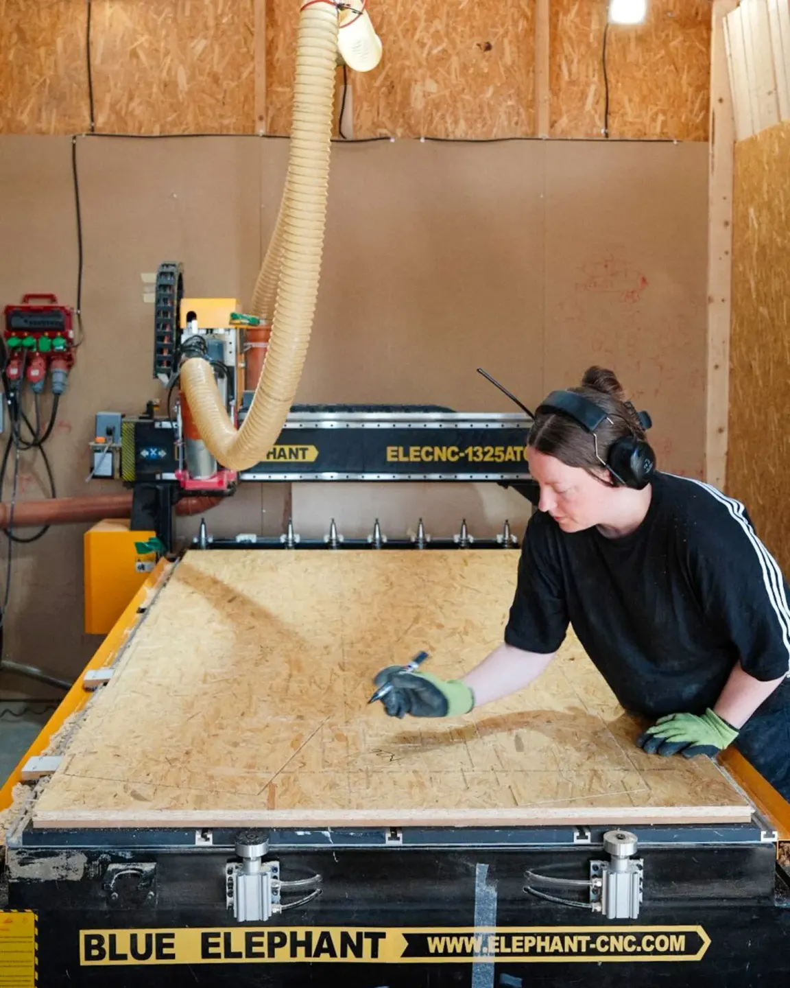 EcoNeo CNC fabrication process showing a timber panel being machined from the digital house model